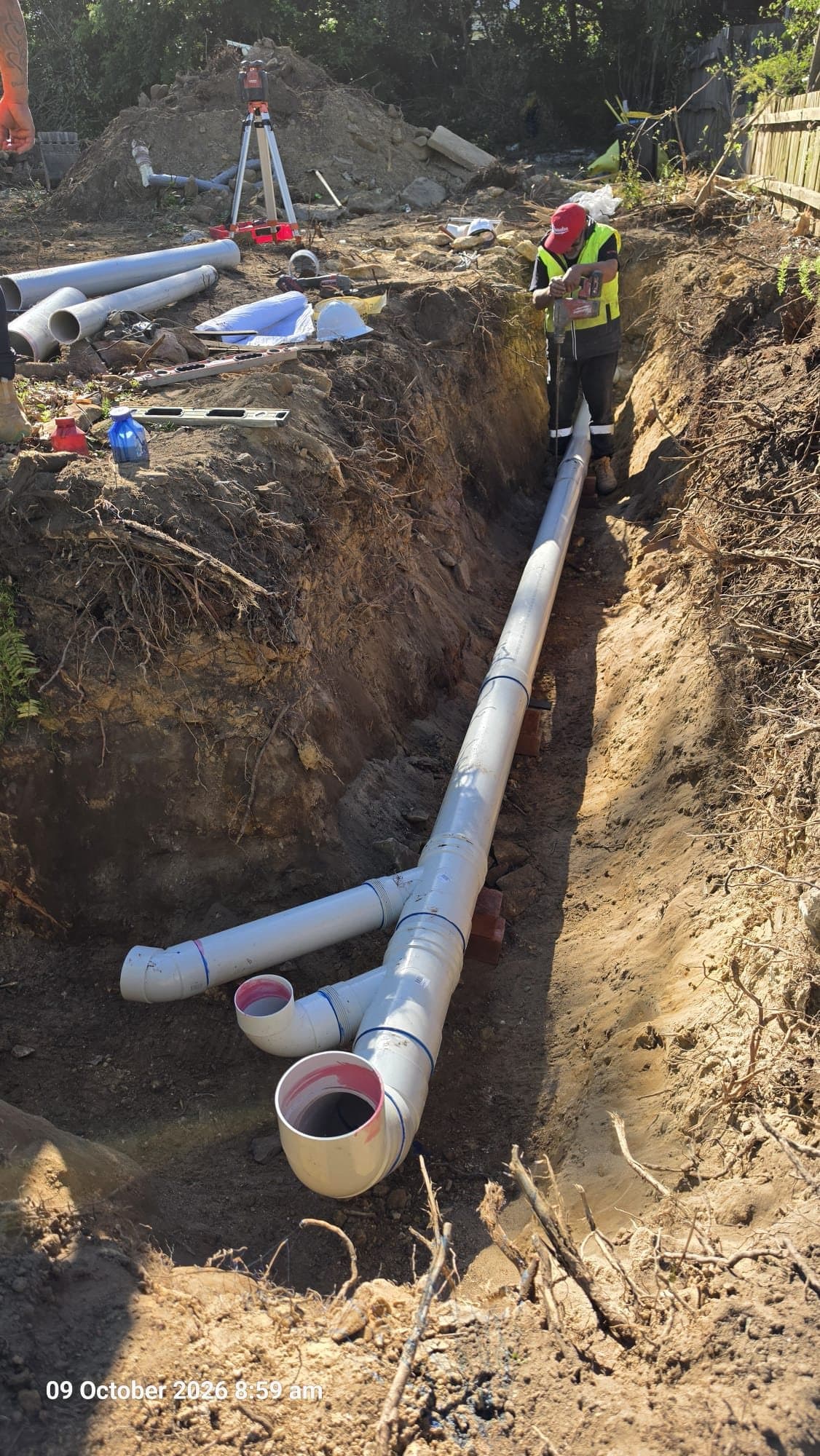 New white PVC sewer side line extension laid on supports in a trench