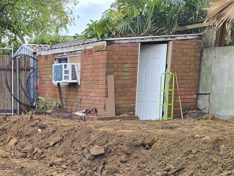 The old brick shed fitted out as the site office, with a new door and air conditioner